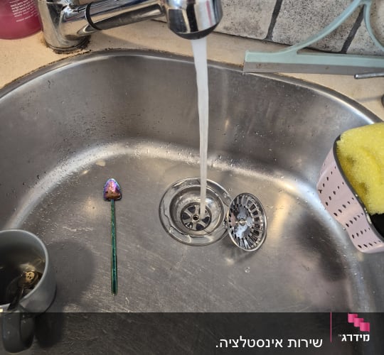 ברז מטבח עם מים זורמים בכיור נירוסטה